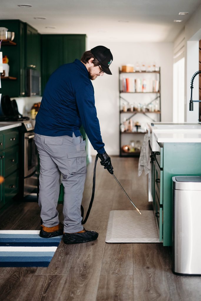 Professional pest control technician at PCI applying treatment inside a home in Collin County, TX